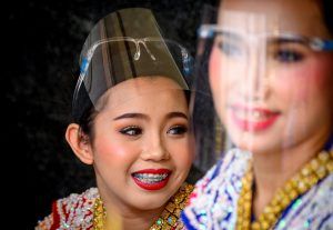 Traditional Thai dancers wearing protective face shields relax after a performance at the Erawan Shrine, which was reopened after the Thai government relaxed measures to combat the spread of the COVID-19 novel coronavirus, in Bangkok on May 4, 2020. - Thailand began easing restrictions related to the COVID-19 novel coronavirus on May 3 by allowing various businesses to reopen, but warned that the stricter measures would be re-imposed should cases increase again. (Photo by Mladen ANTONOV / AFP)